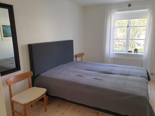 瑟德港Välrenoverad fin lägenhet i charmigt område的卧室配有床、椅子和窗户。