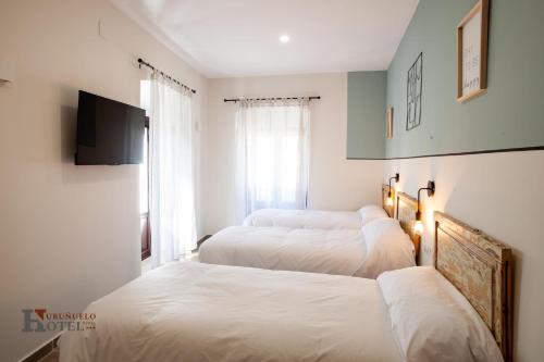 Hotel Rural el Turuñuelo的一间卧室设有三张床和一台平面电视