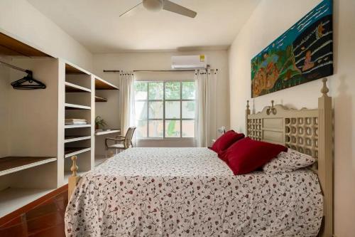 卡塔赫纳JUNTO AL MAR Y EL MANGLAR的一间卧室配有一张带红色枕头的床和一扇窗户