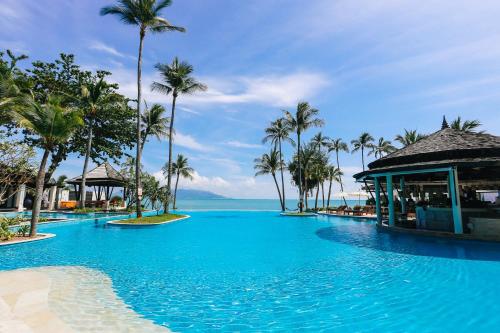 曾蒙海滩Melati Beach Resort & Spa的一座棕榈树和海洋的大型游泳池