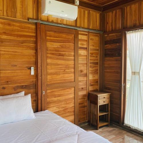 KetewelWell Inn Villa的卧室设有木墙、一张床和窗户
