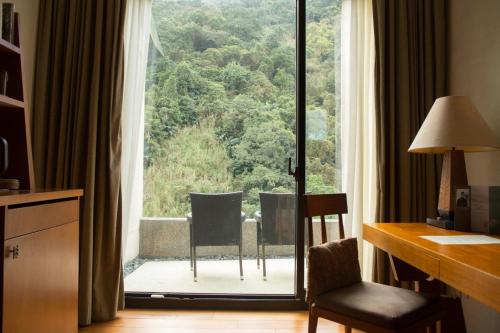 乌来馥兰朵乌来度假酒店的客房设有带桌椅的大窗户。