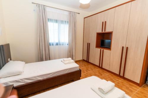 卡萨米尔Xhorxhi villa的一间带两张床、一台电视和橱柜的卧室