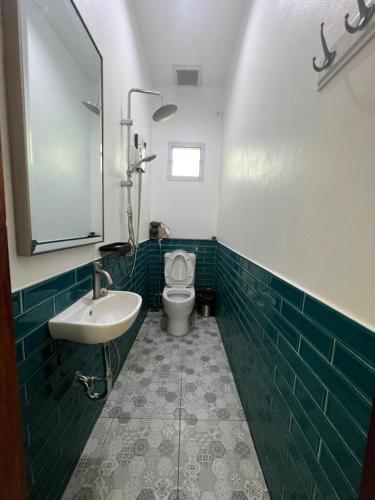 南奔ComeHome Lamphun的绿色瓷砖浴室设有卫生间和水槽