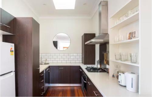 悉尼Steps from Manly Beach的厨房配有棕色橱柜和白色台面
