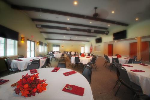 BabbittJunction Inn Suites & Conference Center的宴会厅配有白色的桌子和带红色餐巾的椅子