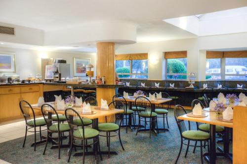约翰内斯堡Road Lodge Randburg的餐厅设有木桌和绿色椅子