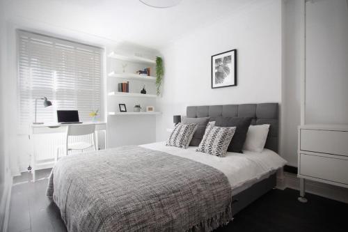 伦敦Luxury 2BR Flat in Hip Notting Hill的白色卧室配有带枕头的床和书桌