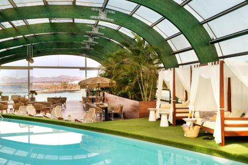 阿雷西费阿瑞斯弗格兰酒店及水疗中心的一个带桌椅的游泳池和玻璃天花板