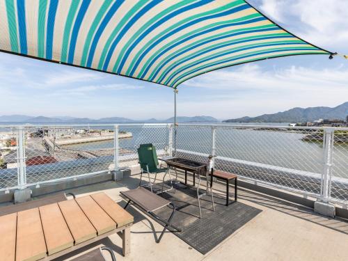 廿日市宫岛奥莫特纳希旅舍的阳台配有桌子、椅子和雨伞。