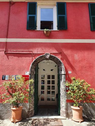 斯培西亚Boutique Hotel Novecento的红色建筑的入口,有两株盆栽植物