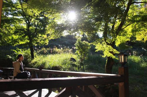 雾岛市星空に包まれる 森の隠れ家　Amrita Lodge ~stay & retreat~的坐在公园长凳上的女人