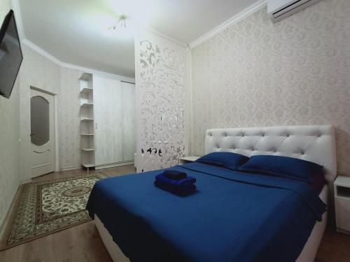 奇姆肯特Апартаменты в жилом комплексе БИИК的一间位于客房内的蓝色床卧室