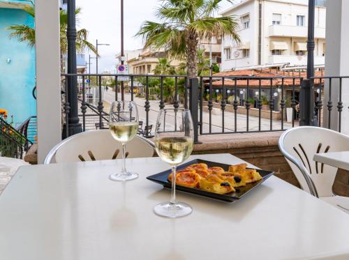 里米尼Hotel Greta B&B的一张桌子,上面放着两杯葡萄酒和一盘食物
