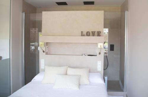 阿斯托加Astorga suites的卧室配有白色床,上面有爱情标志