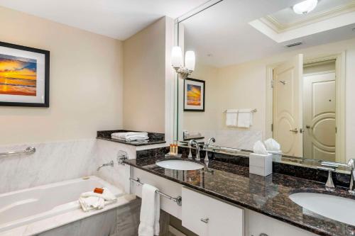 蓬塔戈尔达Wyvern Hotel, Ascend Hotel Collection的浴室配有2个盥洗盆、浴缸和大镜子