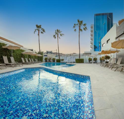 佩尼斯科拉Hotel RH Portocristo & Wellness的一个带椅子的游泳池,棕榈树