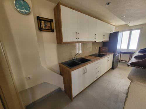 萨兰达Villa Sotiri的厨房配有白色橱柜、水槽和时钟