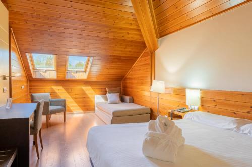 潘通IBERIK Augas Santas Balneario & Golf的客房设有两张床、椅子和沙发。