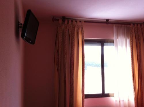 本比夫雷Hostal Tio Pepe I的一间窗户的房间,墙上有一台电视机