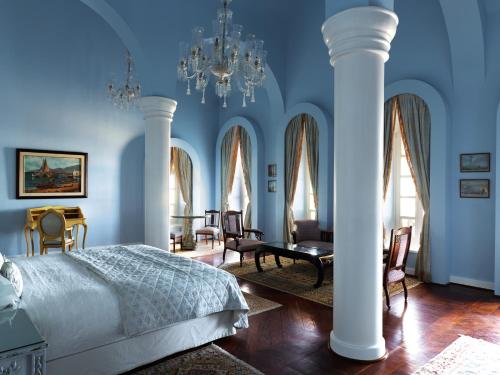 赫尔格达La Maison Bleue El Gouna的卧室设有蓝色的墙壁、白色的柱子和一张床