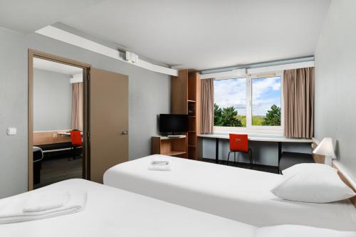 布达佩斯Ibis Budapest Citysouth的酒店客房设有两张床、一张桌子和一面镜子