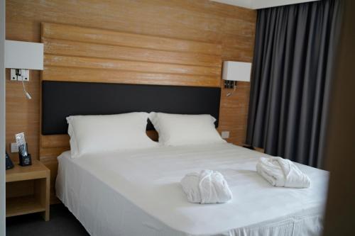 卡坦扎罗丽都PM Hotel的一间卧室配有一张带白色毛巾的床