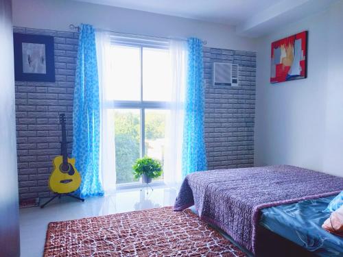 曼达维市Arthomes BB6的一间卧室配有一张床,窗户配有吉他