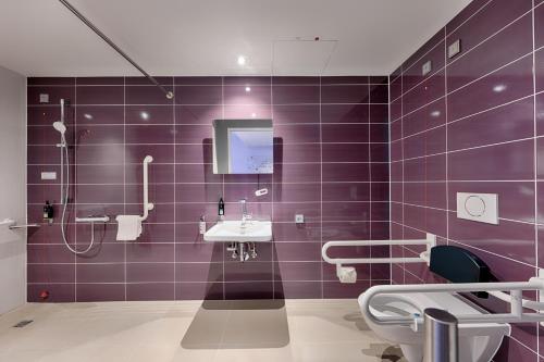 杜塞尔多夫Premier Inn Düsseldorf City Friedrichstadt的紫色浴室设有水槽和镜子