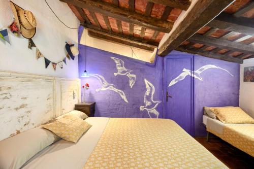 圣胡安-德拉斯阿巴德萨斯El Colomar, El Reixac Casa Rural的一间卧室,墙上有紫色的墙壁,上面有鸟儿画