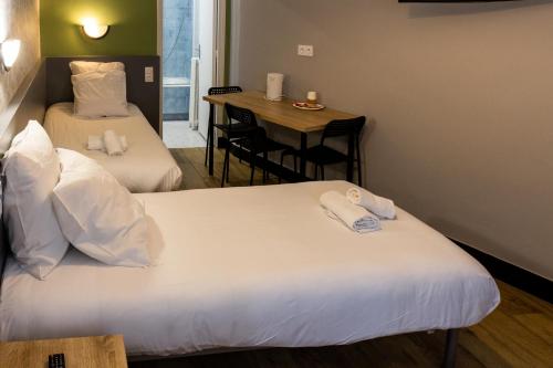 巴黎卢克西亚酒店的酒店客房设有两张床和一张桌子。