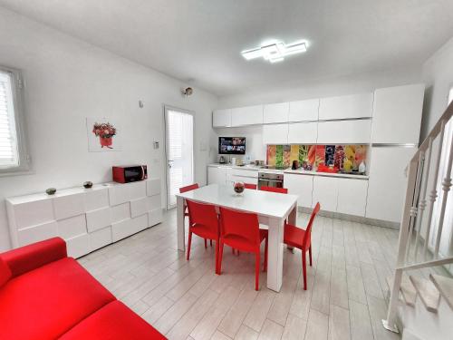 贝瓦尼亚圣彼得Villa Roberta Spiaggiabianca Deluxe - A 20 metri dal mare的厨房配有白色的桌子和红色的椅子