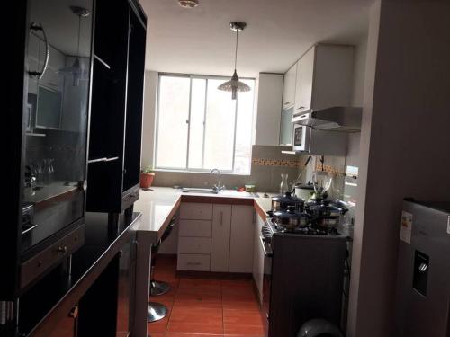 利马Hermoso Duplex en Chorrillos的厨房配有炉灶、水槽和窗户。