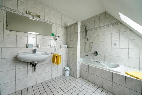 玛特丁恩Gasthof Hotel zum Rebstock的白色的浴室设有水槽和浴缸。