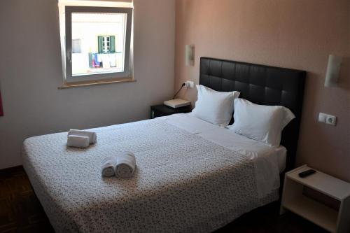 米尔芳提斯城Alojamentos Vitinho - Vila Nova Milfontes的一间卧室配有一张床,并备有2个拖鞋