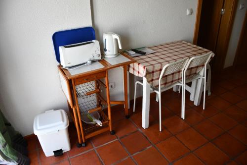 米尔芳提斯城Alojamentos Vitinho - Vila Nova Milfontes的小桌子和椅子上带缝 ⁇ 机