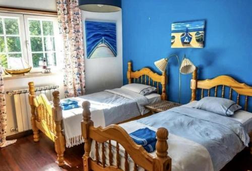 阿尔科巴萨Fantastic house swimmingpool jacuzzi horses的卧室设有两张床铺和蓝色的墙壁