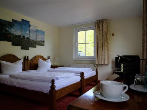 诺因多夫Hotel Heiderose Hiddensee的一间卧室配有两张床和一张桌子,上面有杯子