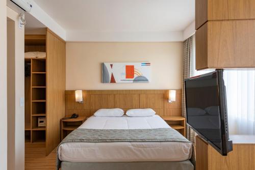 圣若泽杜斯坎普斯Monreale Plus São José dos Campos的一间卧室配有一张床和一台平面电视