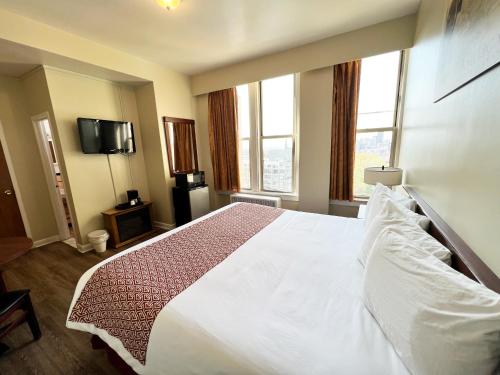 布法罗莱诺克斯酒店和套房的卧室设有一张白色大床和两个窗户。