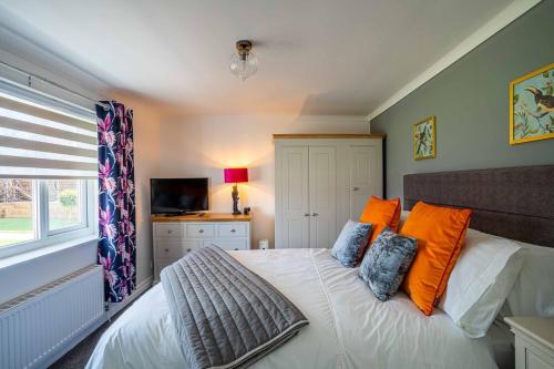 Upholland1 The Cottage的一间卧室配有带橙色枕头的床和电视。