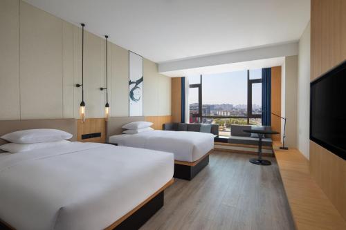 丹阳丹阳万枫酒店的酒店客房设有两张床和一台平面电视。