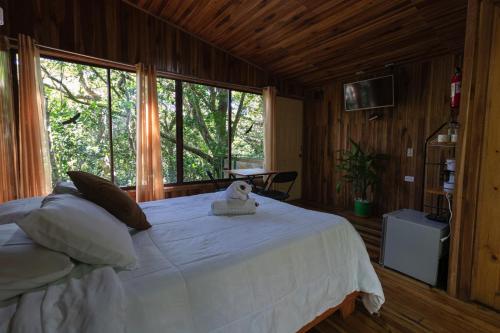 蒙泰韦尔德哥斯达黎加The Green Tree Lodge的卧室配有一张白色的床,上面有一只动物填充物