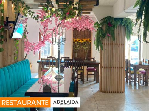圣克里斯托瓦尔-德拉斯卡萨斯Hotel Pepe Pancho的餐厅设有桌椅和粉红色的鲜花