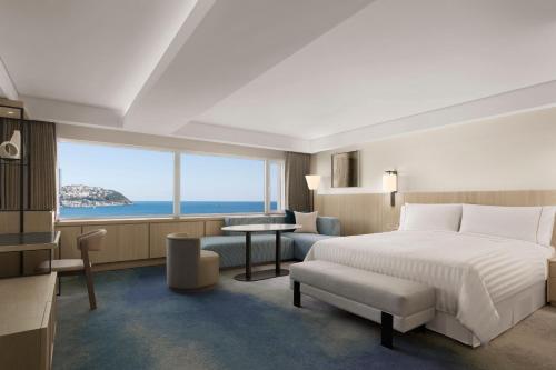 釜山The Westin Josun Busan的酒店客房设有一张床,享有海景。