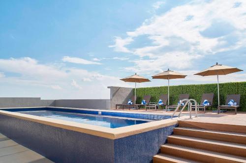 阿瓜斯卡连特斯Fairfield Inn & Suites by Marriott Aguascalientes的一座大楼内的游泳池,配有椅子和遮阳伞
