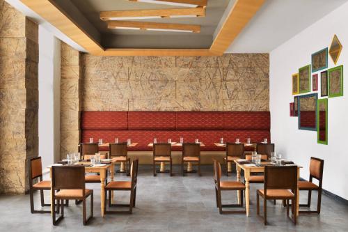 艾哈迈达巴德Fairfield by Marriott Ahmedabad的一间带桌椅和红色长凳的餐厅