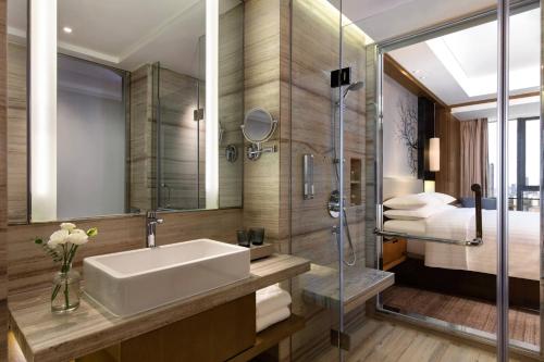 长沙长沙中建万怡酒店的一间带水槽和淋浴的浴室以及一张床