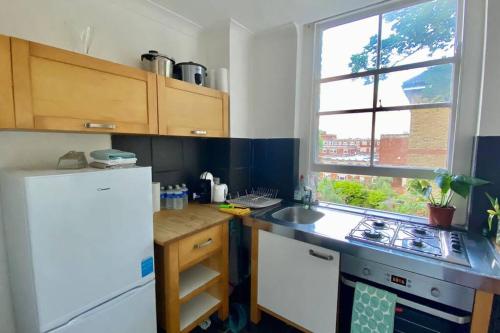 伦敦2 Bedroom Flat in Camberwell Green - Central Location with excellent connections to tourist attractions and main London airports的厨房配有白色冰箱和水槽