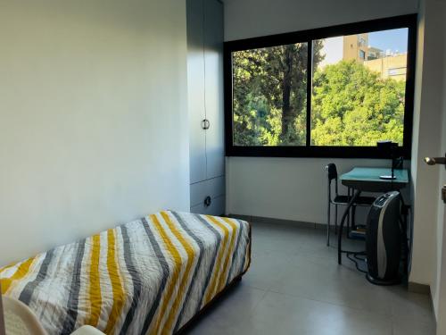 海法2-bd apartment at the heart of the Carmel的一间卧室配有一张床、一张书桌和一个窗户。